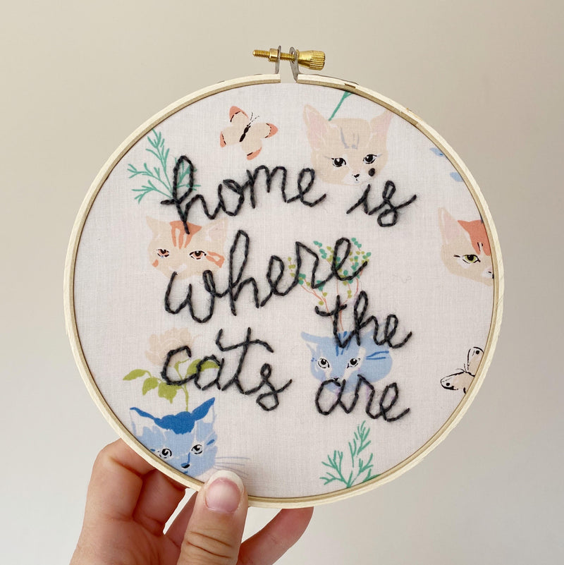 hand-stitched embroidery with text that reads "home is where the cats are" and cat patterned fabric